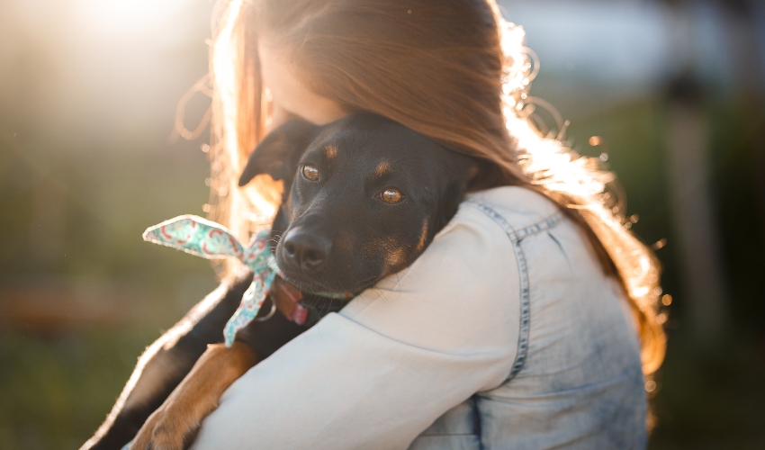 Happy pet mom cuddling her dog on Mother’s Day